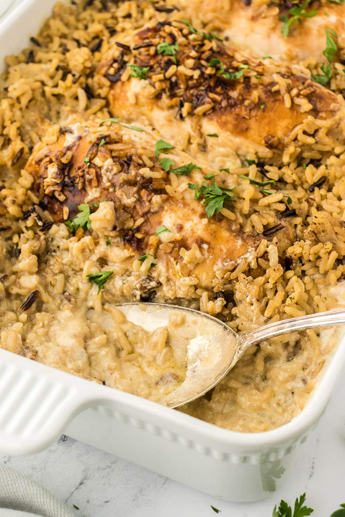 Baked chicken and rice in a casserole dish, with a serving spoon.