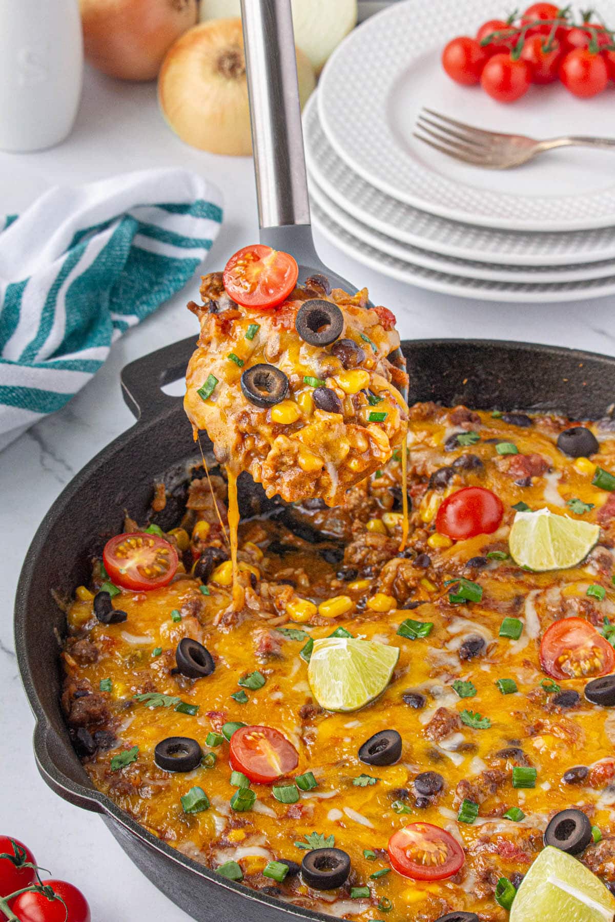 Cast iron skillet filled with Taco and Rice Casserole. With a serving spoon scooping up a serving.