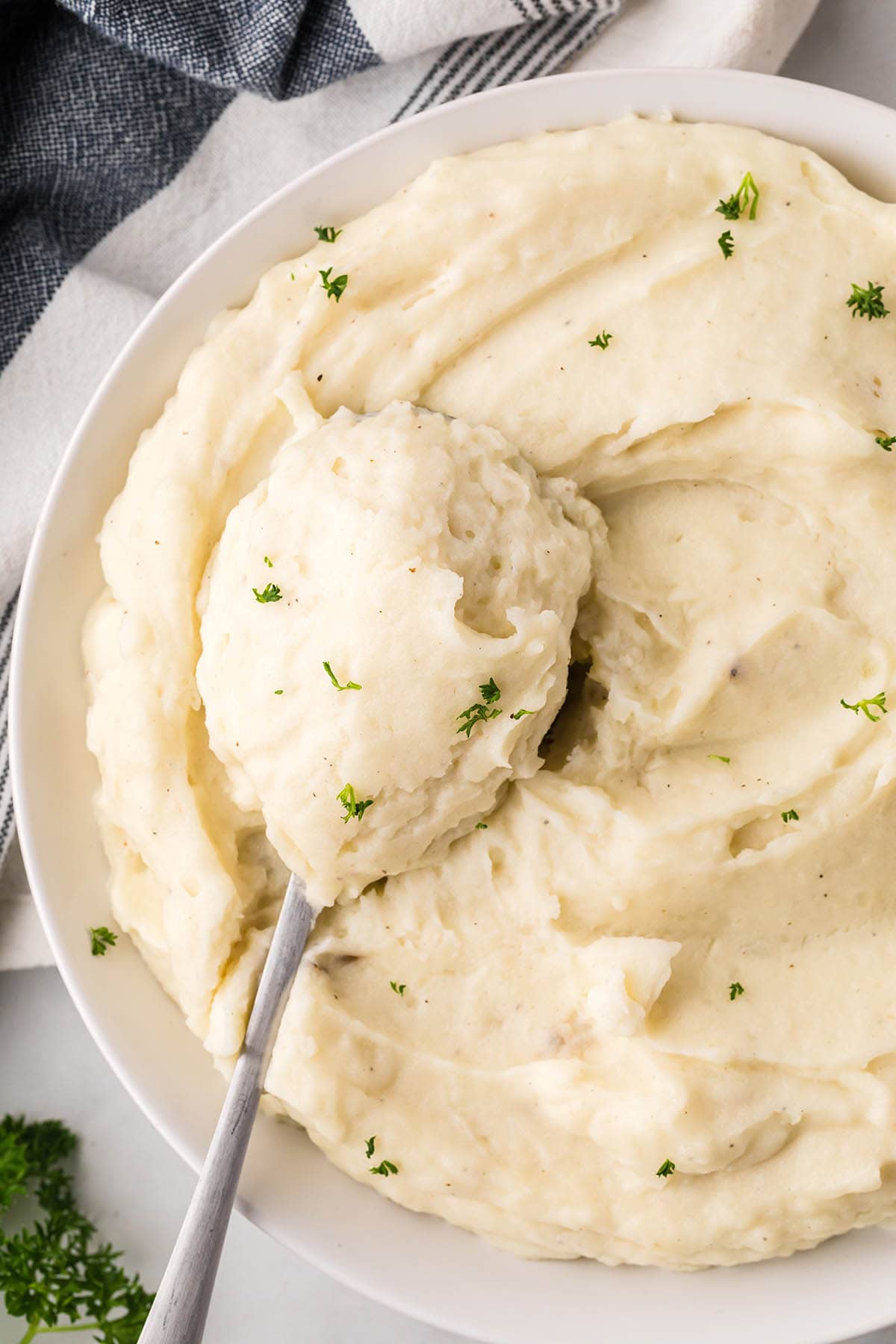 A large bowl filled with creamy mashed potatoes, with a serving spoon.