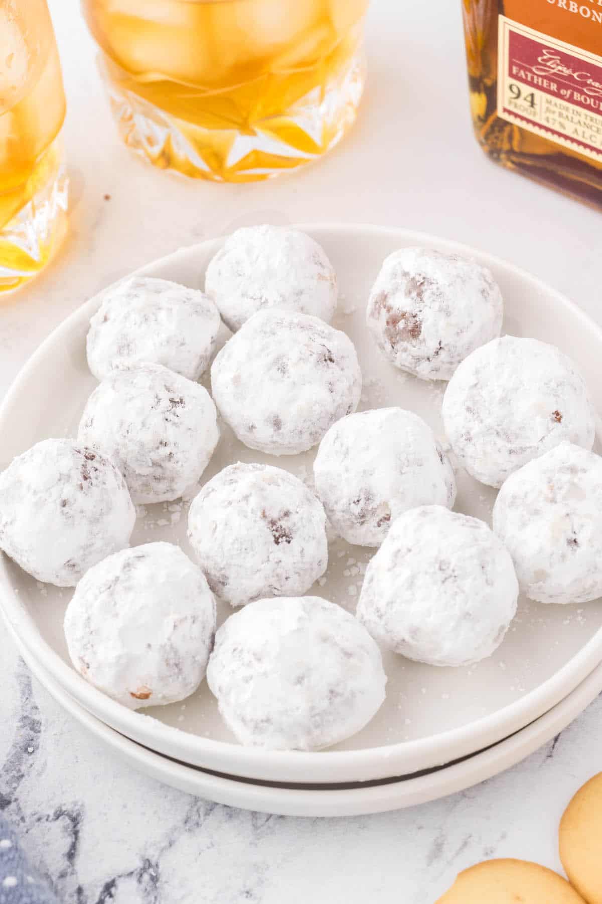 A plate filled with Pecan Bourbon Balls coated with powdered sugar.