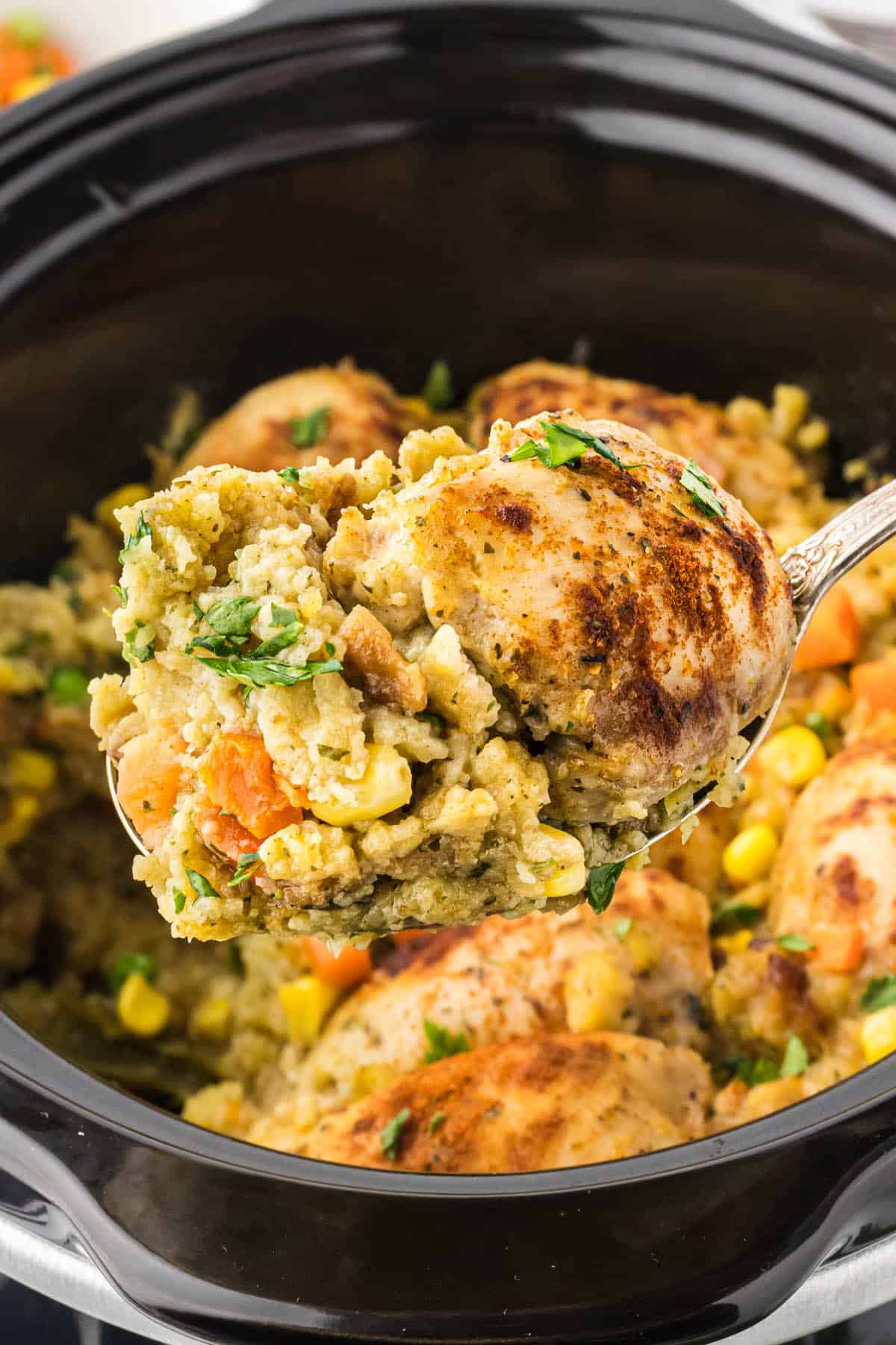 Slow Cooker Chicken and Stuffing in a crockpot with a serving spoon dishing out a serving.