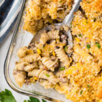 Cheesy pasta casserole in a baking dish, with a serving spoon.