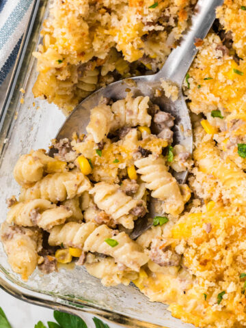 Cheesy pasta casserole in a baking dish, with a serving spoon.