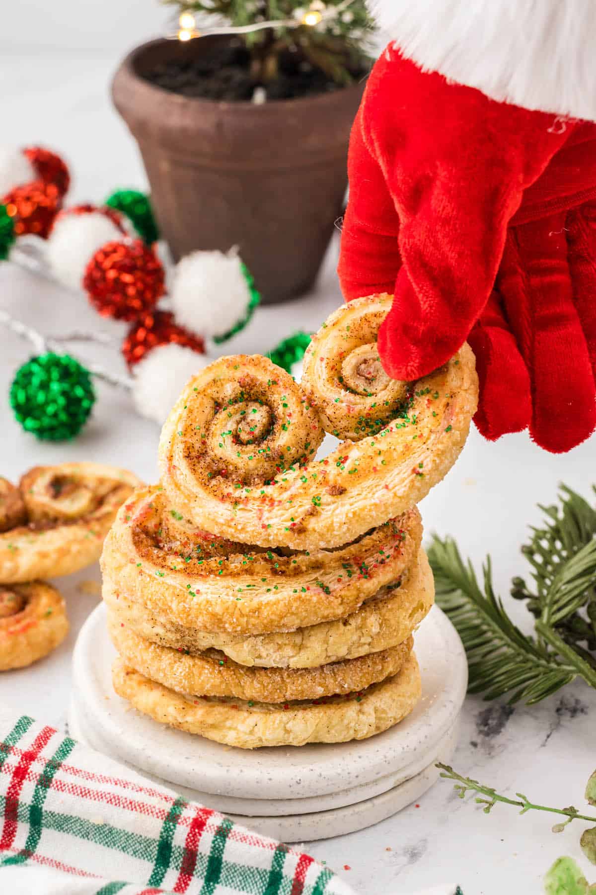 Petite Palmiers stated on a small plate. Santa's glove is reaching down and grabbing a cookie.
