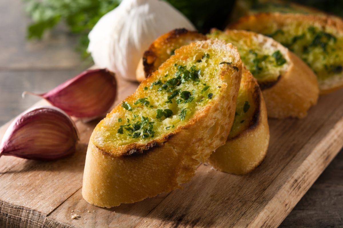 Toasty garlic bread on wooden cutting board.