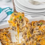 Cheesy rice and beef casserole in a baking dish with a spoon.