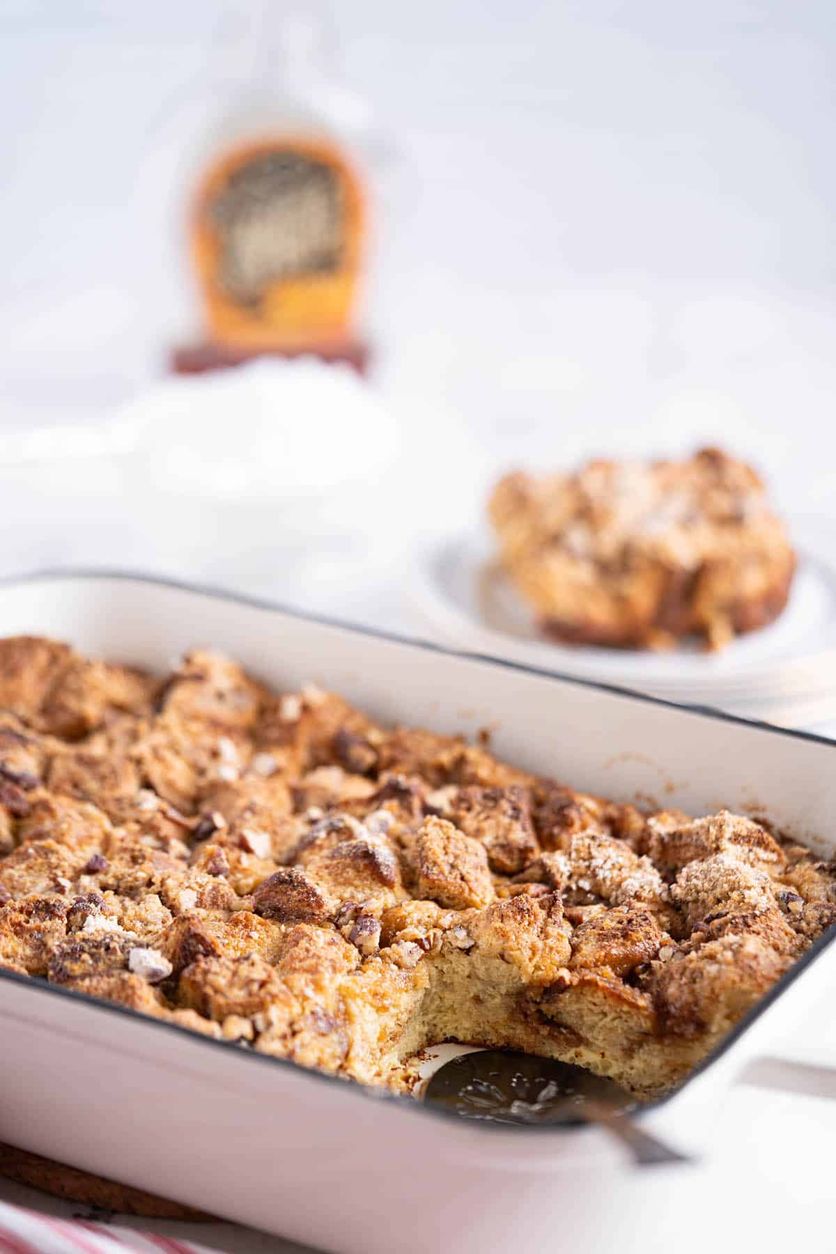 A casserole dish filled with Brioche French Toast Casserole with one slice removed.