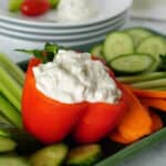 Blue cheese dip spooned into a red bell pepper. Surrounded by vegetables.