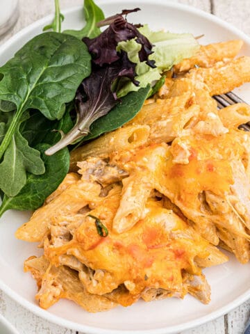 Cheesy pasta on a plate with a green salad.
