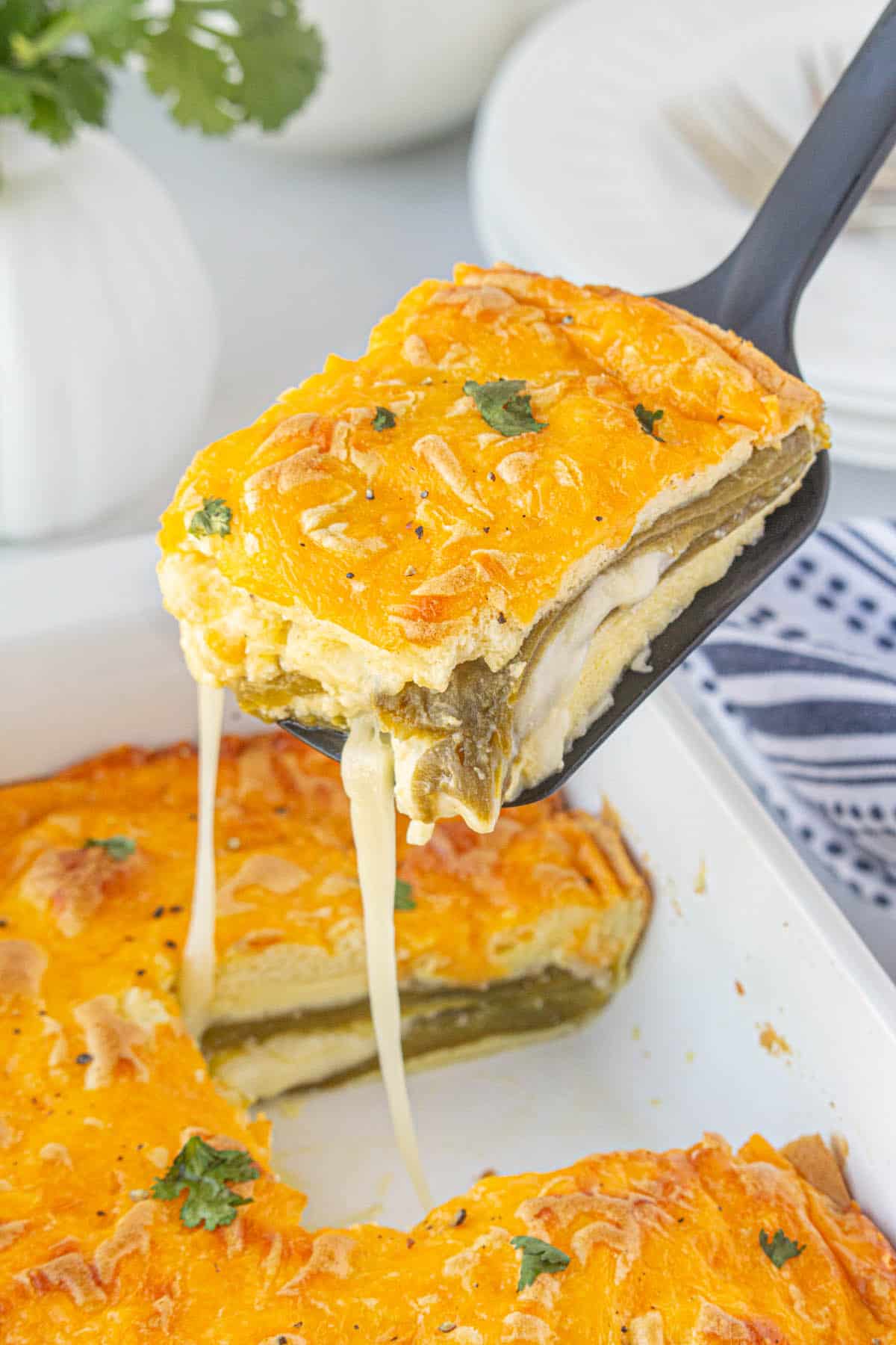 Cheesy Chile Rellenos Casserole with a spatula dishing out a serving.