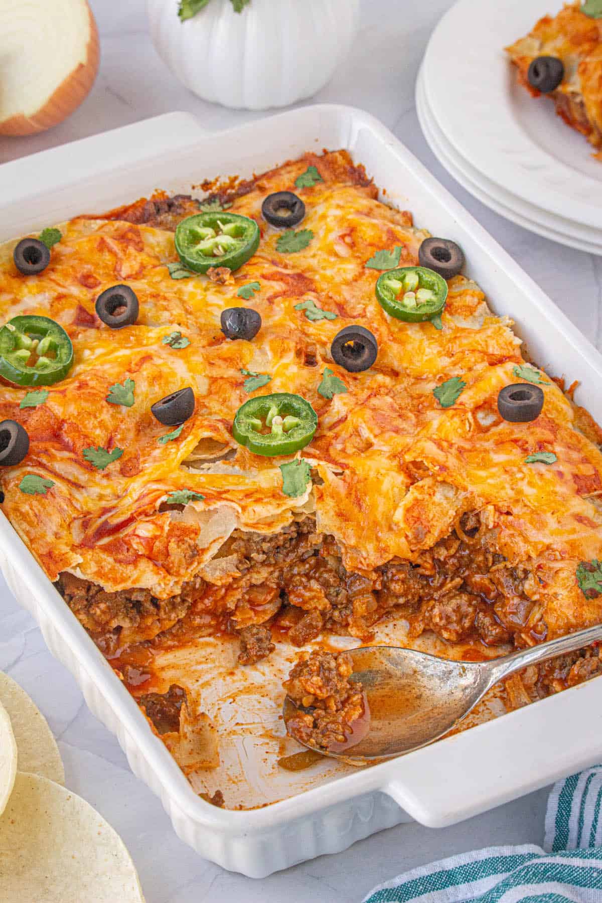 Ground beef enchilada casserole in a baking dish with a serving spoon.