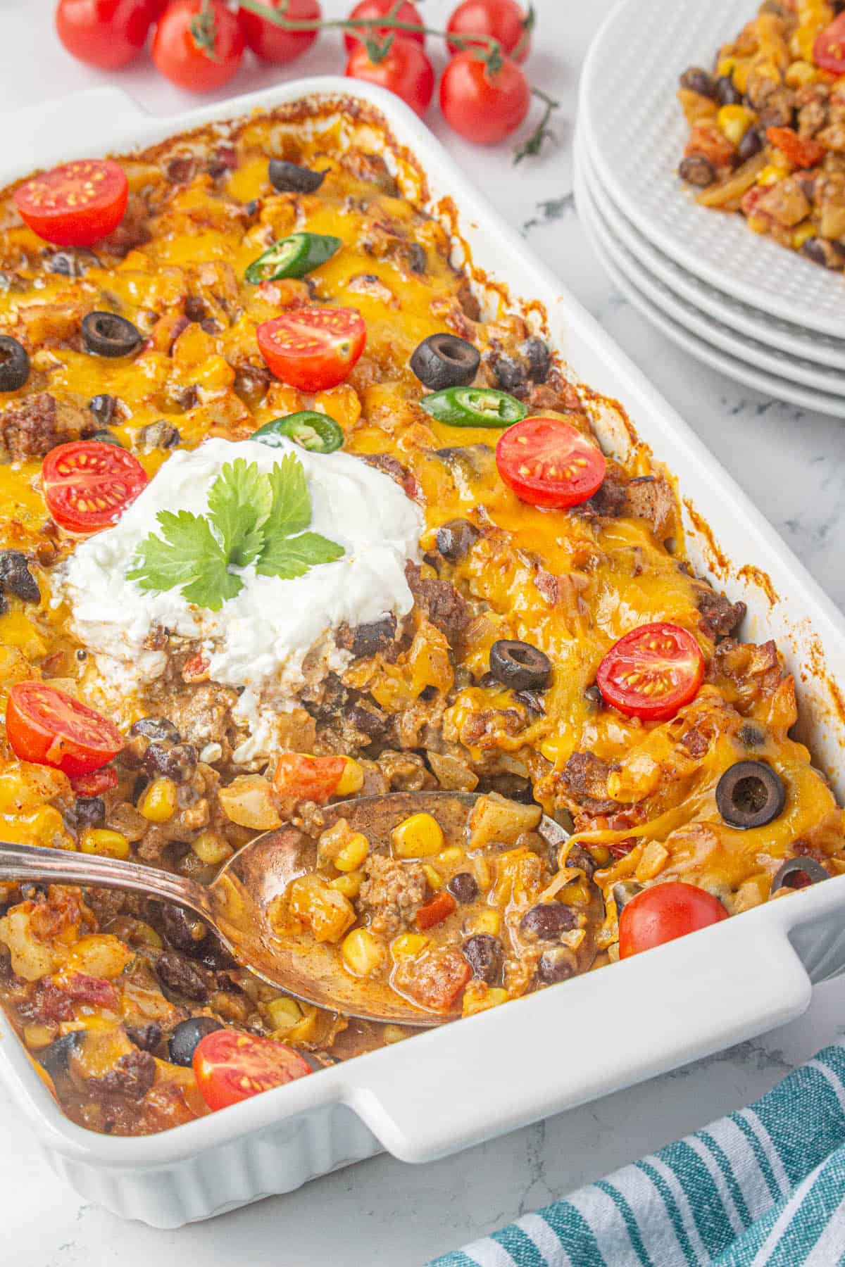 Taco casserole in a baking dish with a serving spoon.