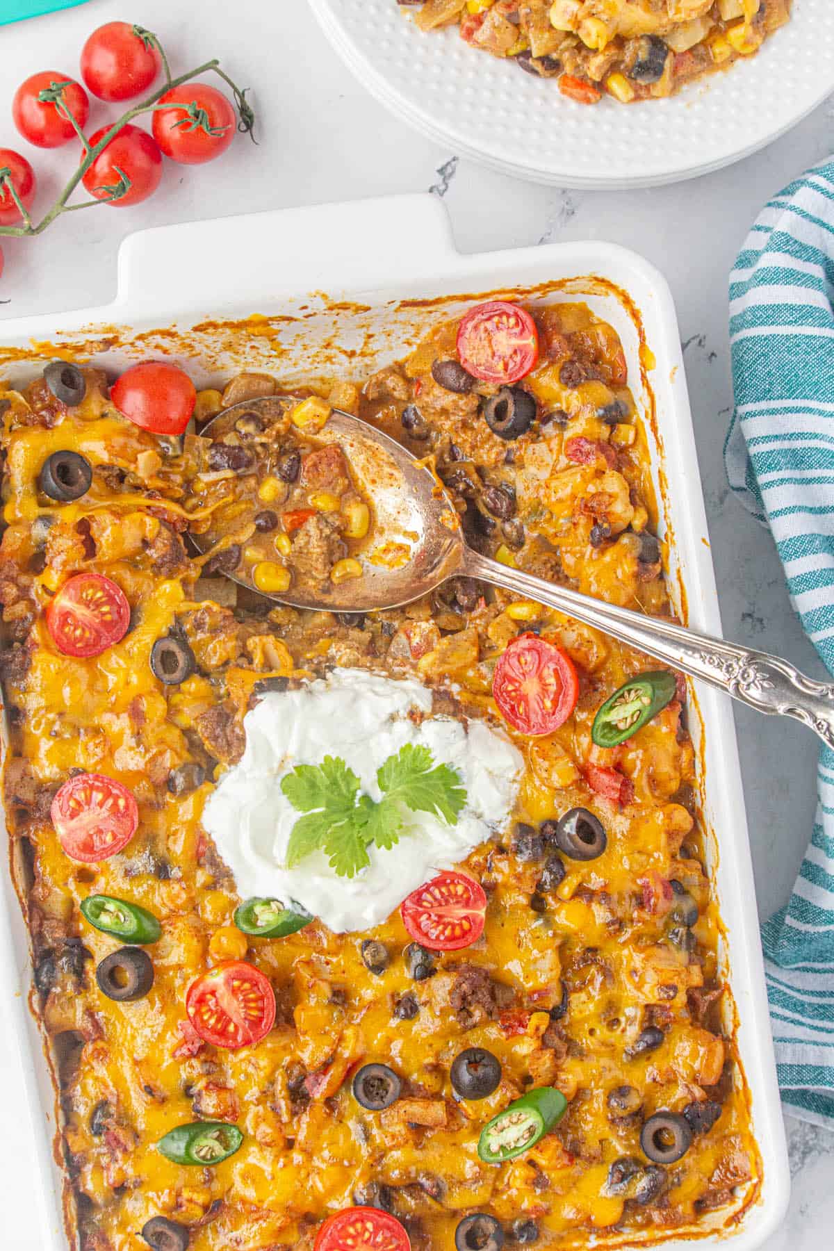 Taco Hashbrown Casserole in a baking dish topped a serving spoon.