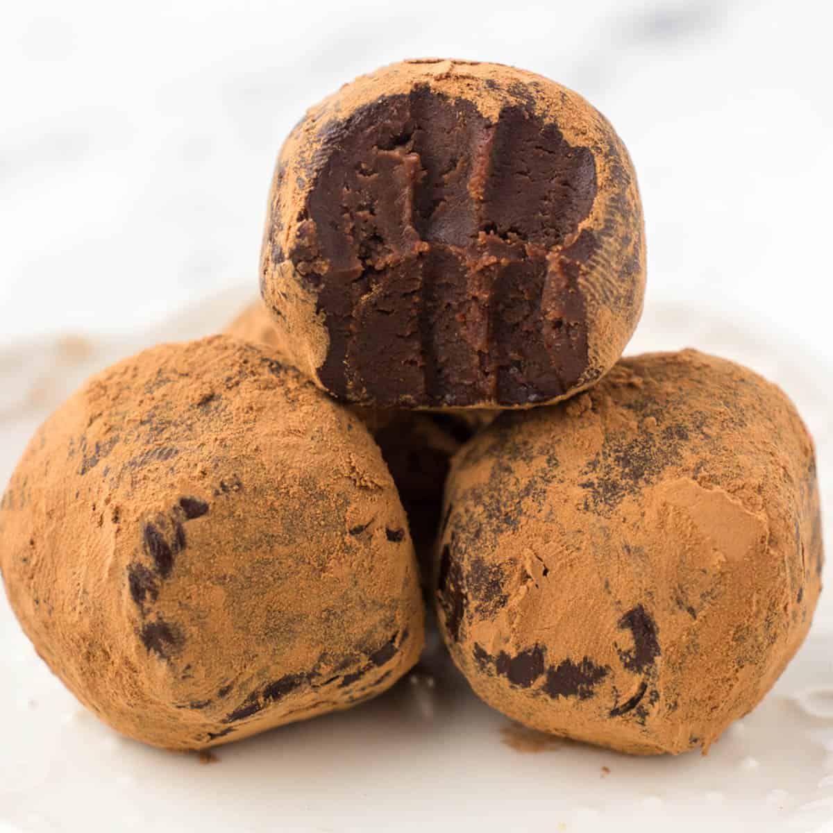 Dark chocolate Kahlua truffles coated in cocoa powder in a pretty white bowl.