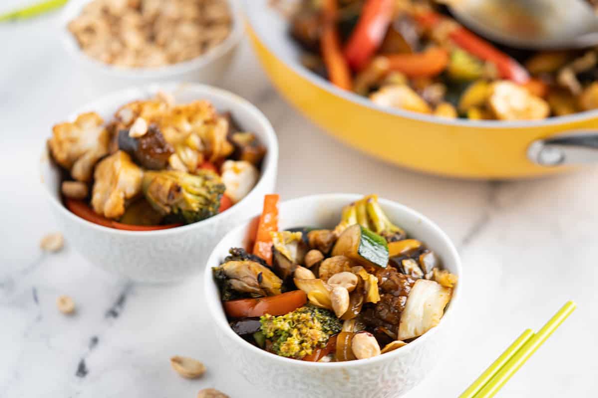 Stir fry vegetables in small bowls topped with peanuts.