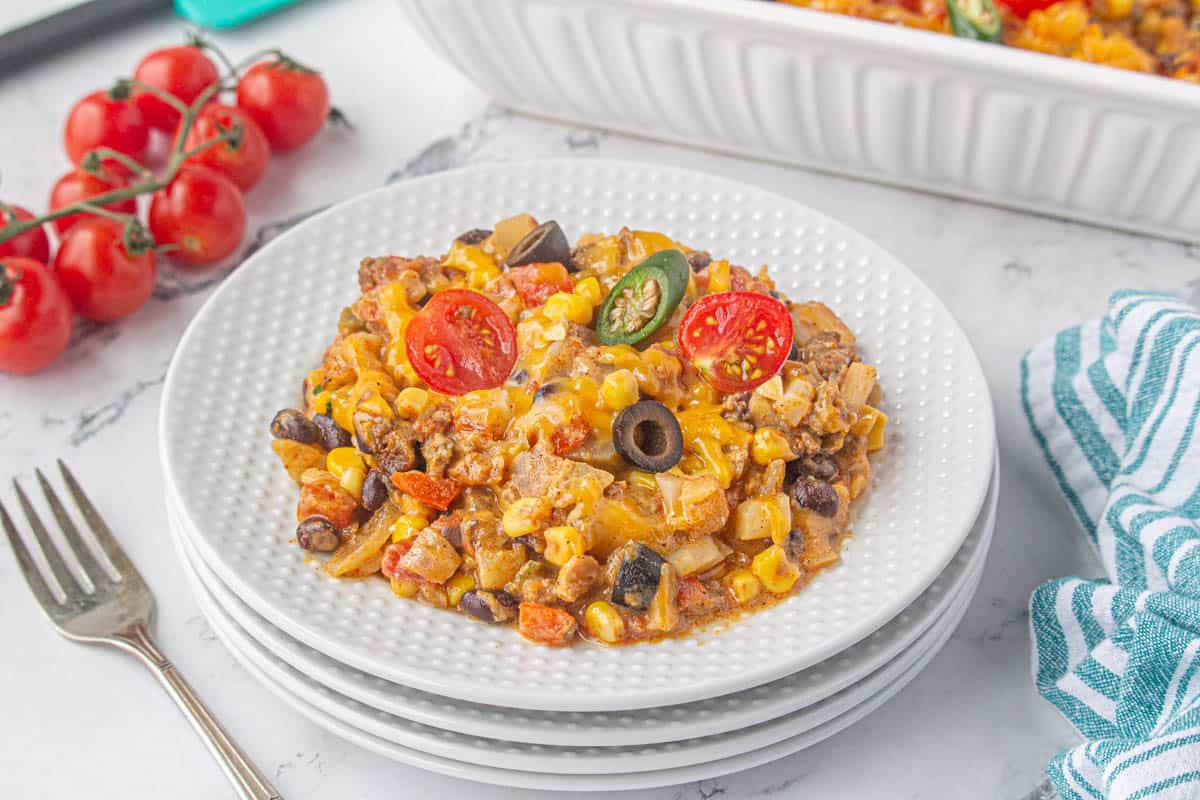 Taco casserole dished up on a plate with a fork off to the side.