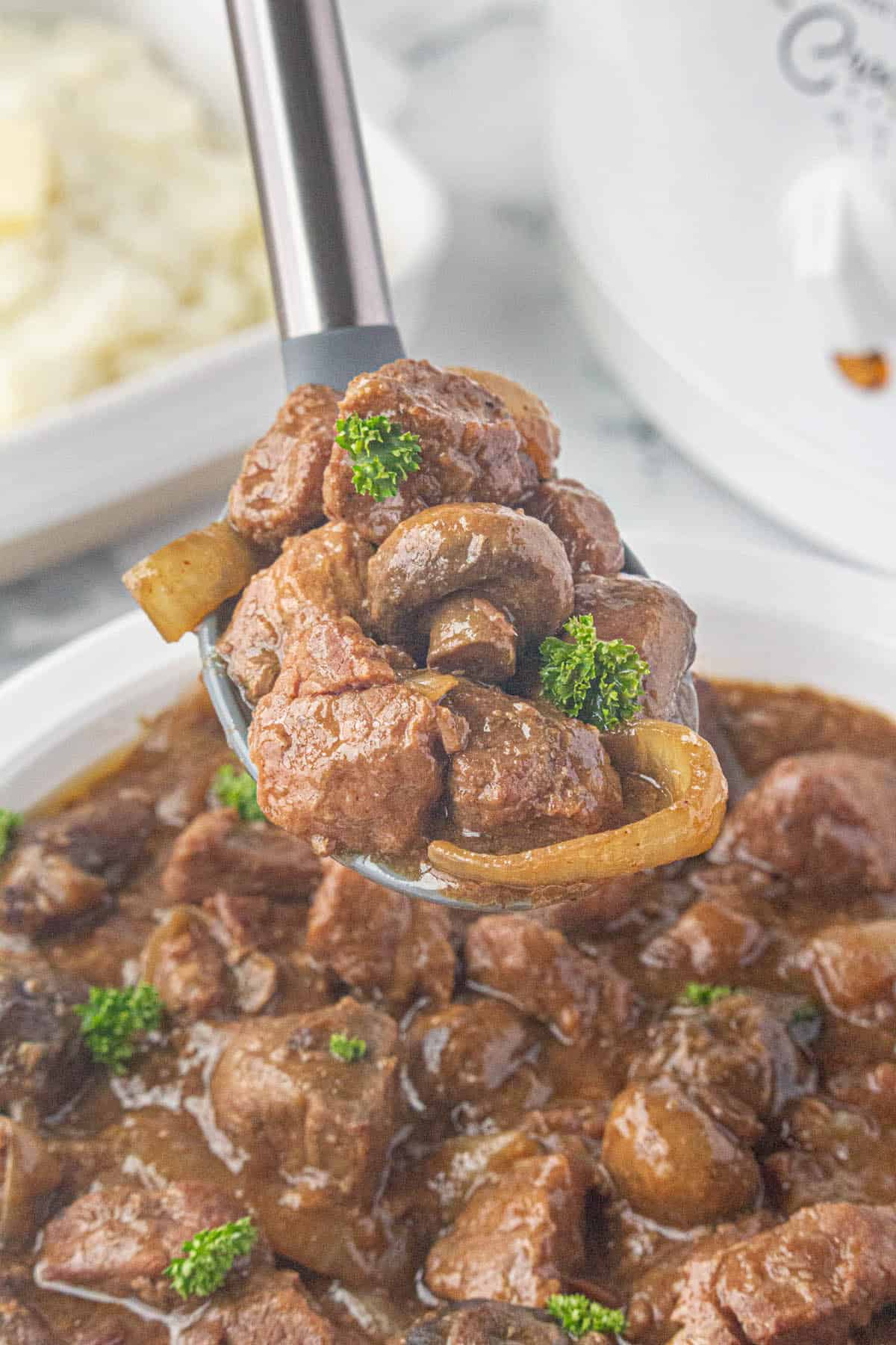 Steak bites in a rich brown gravy with a serving spoon.