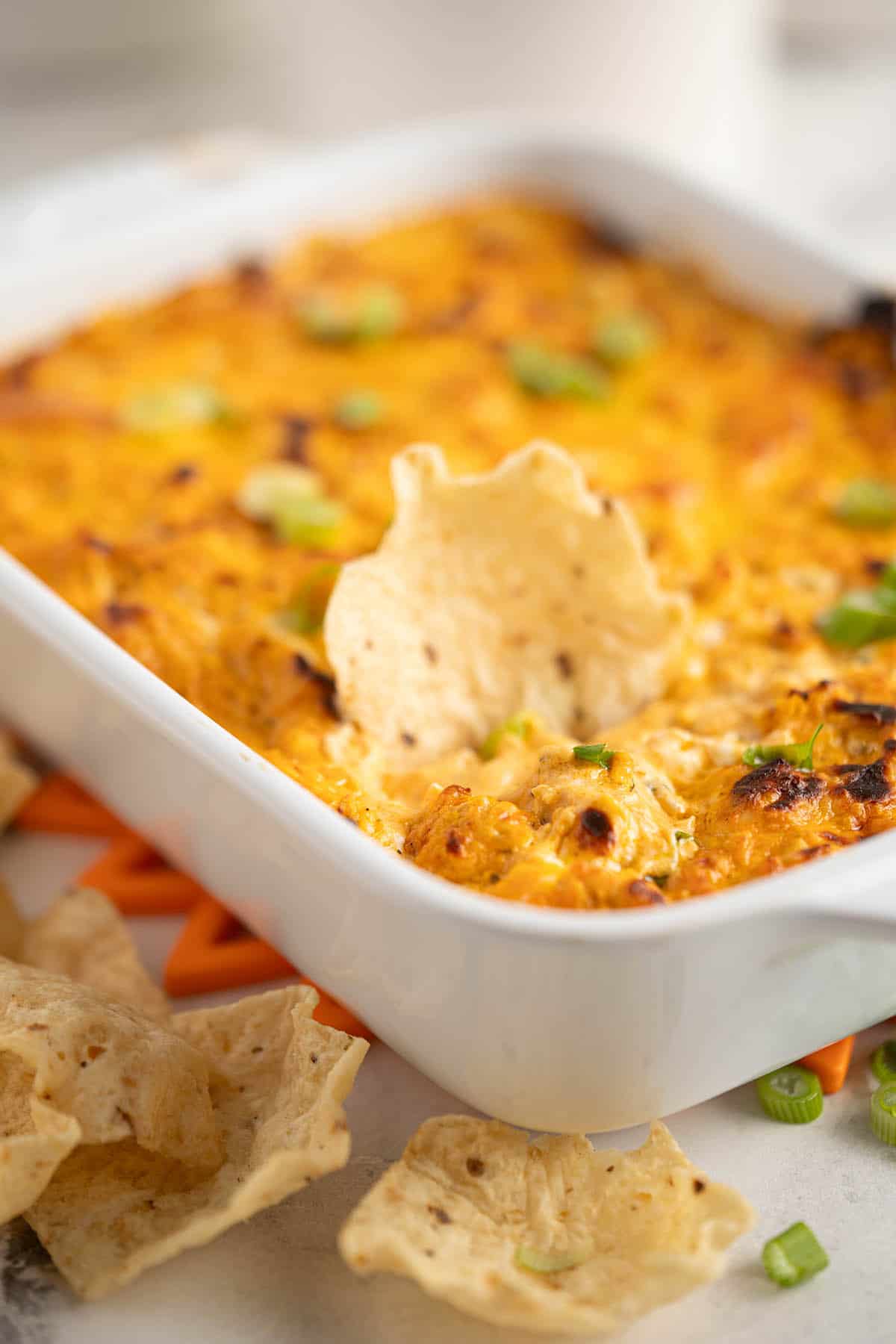 Cheesy buffalo chicken dip in a baking dish, served with chips.