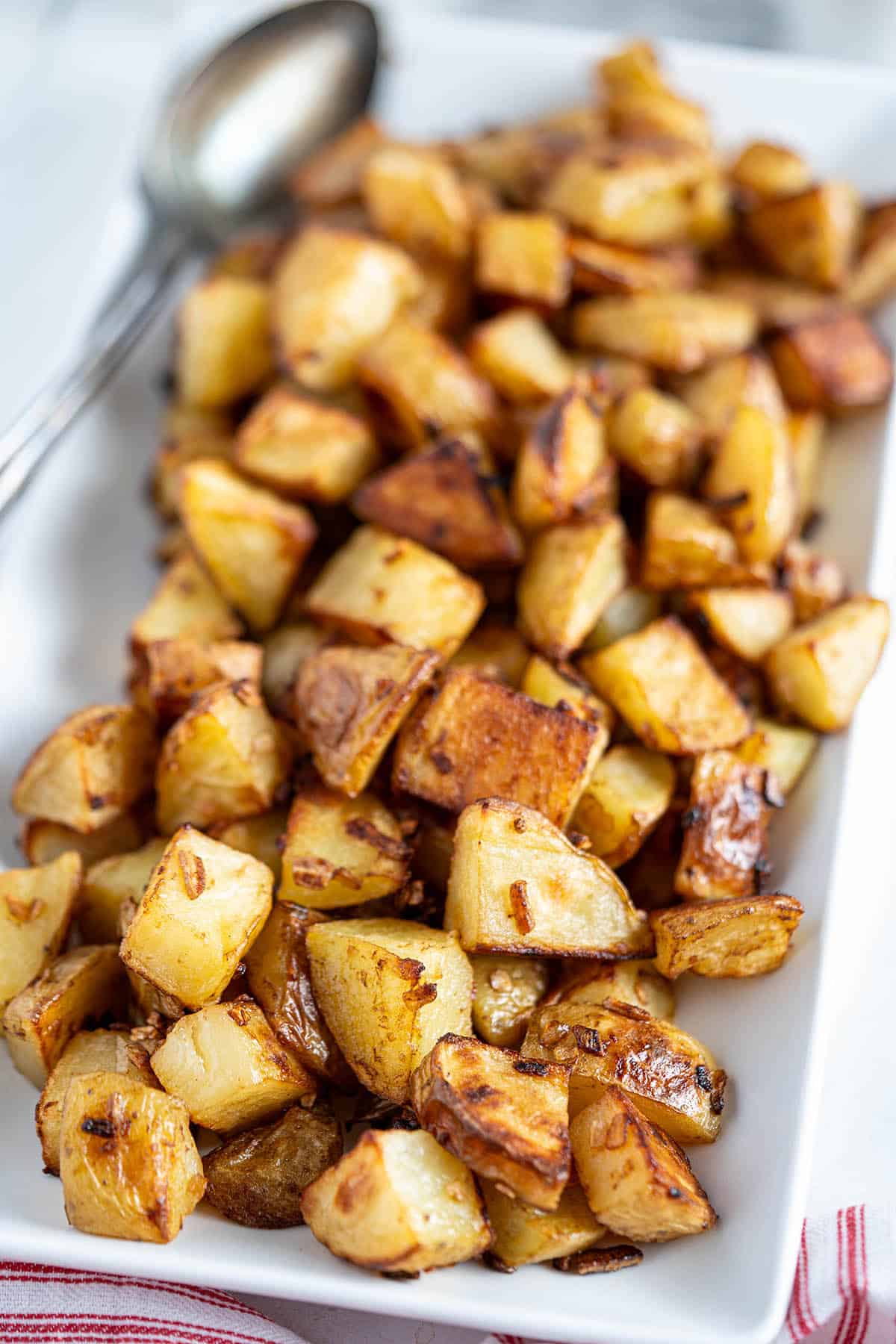 Roasted Potatoes on a platter with a serving spoon.