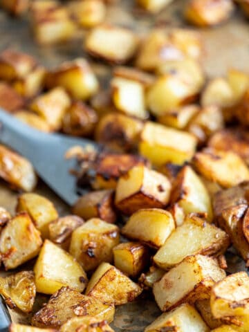 Lipton onion soup mix roast potatoes on a sheet pan with a spatula dishing up a serving.