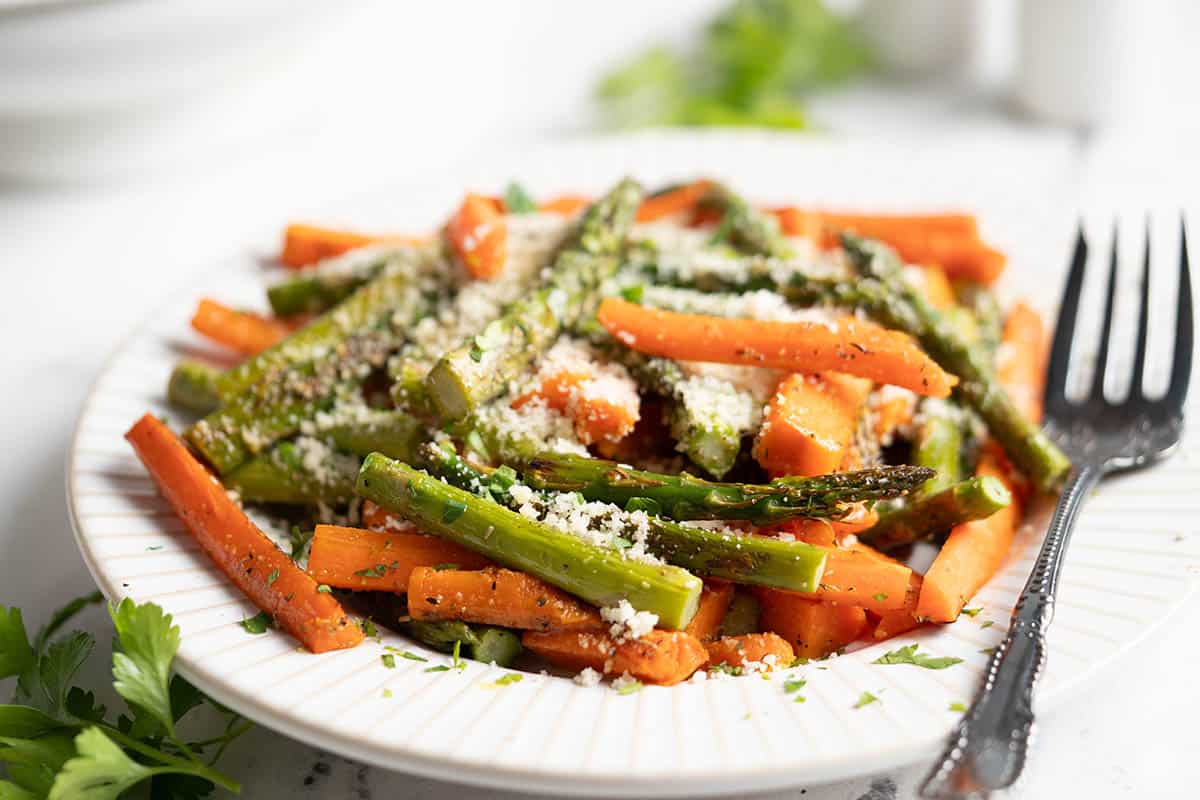 A platter filled with roasted vegetables with a serving utensil on the side.