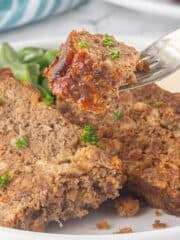 Slices of meatloaf on a plate with a fork stabbing a bite.