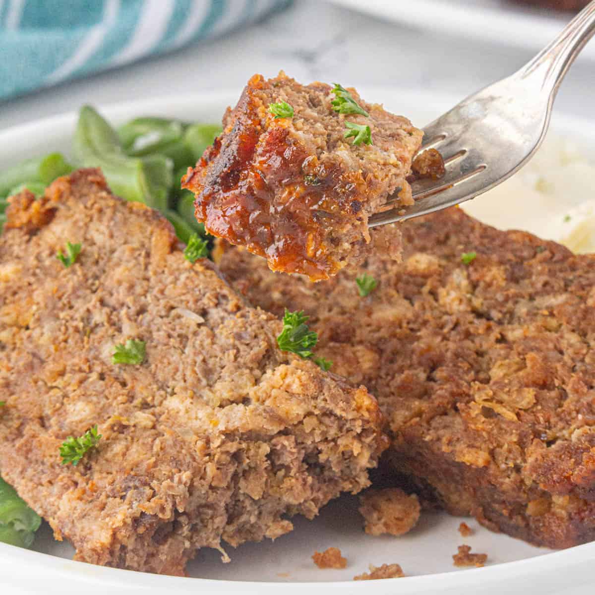 Slices of meatloaf on a plate with a fork stabbing a bite.
