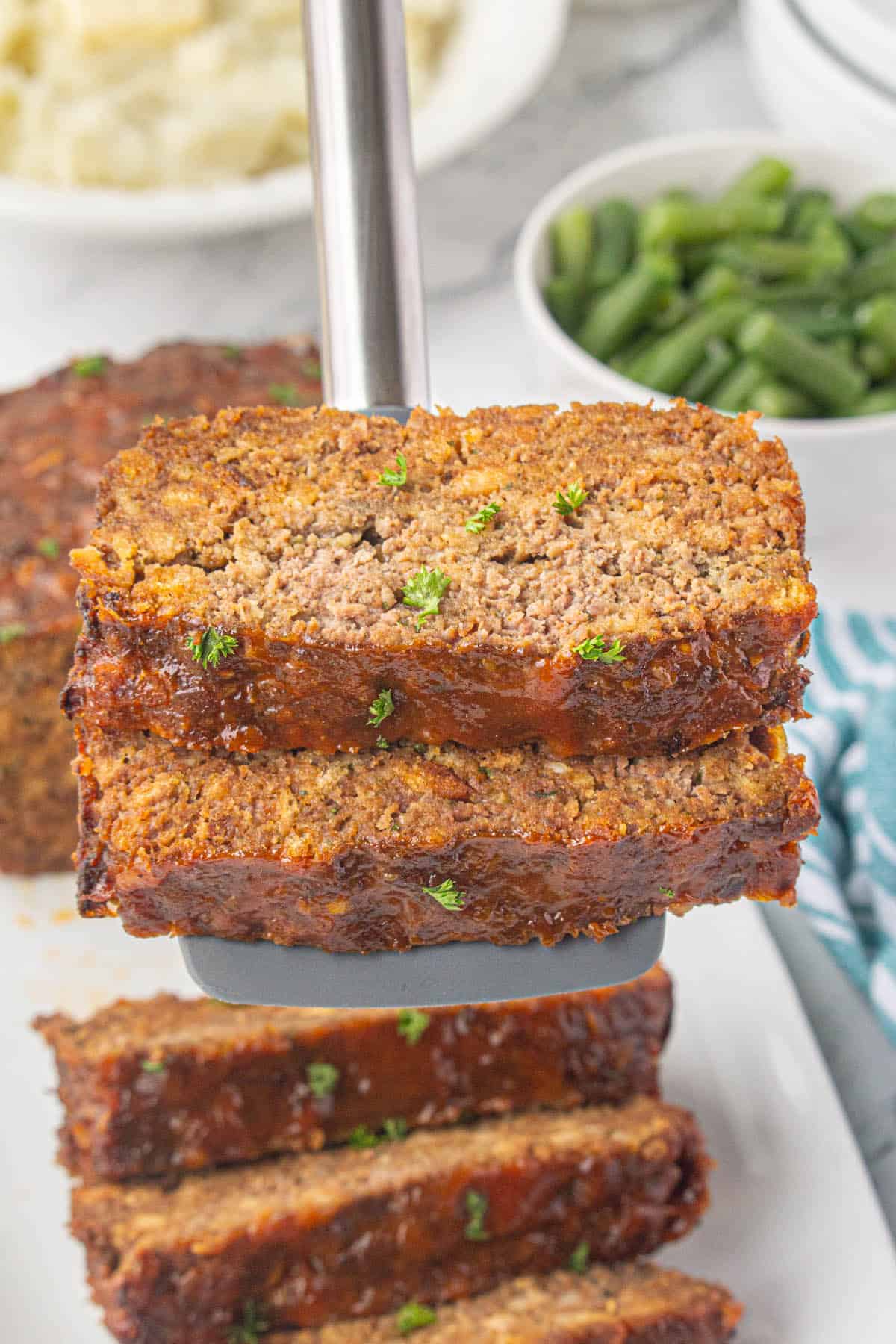 Sliced 5 ingredient Meatloaf with Stuffing, with a spatula serving a slice.