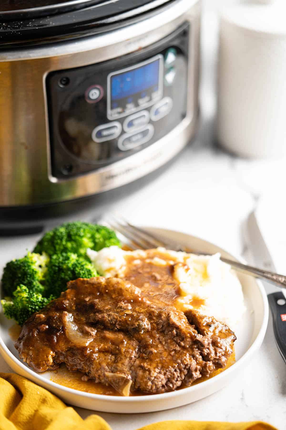Slow Cooker Cube Steak smothered in gravy over potatoes.