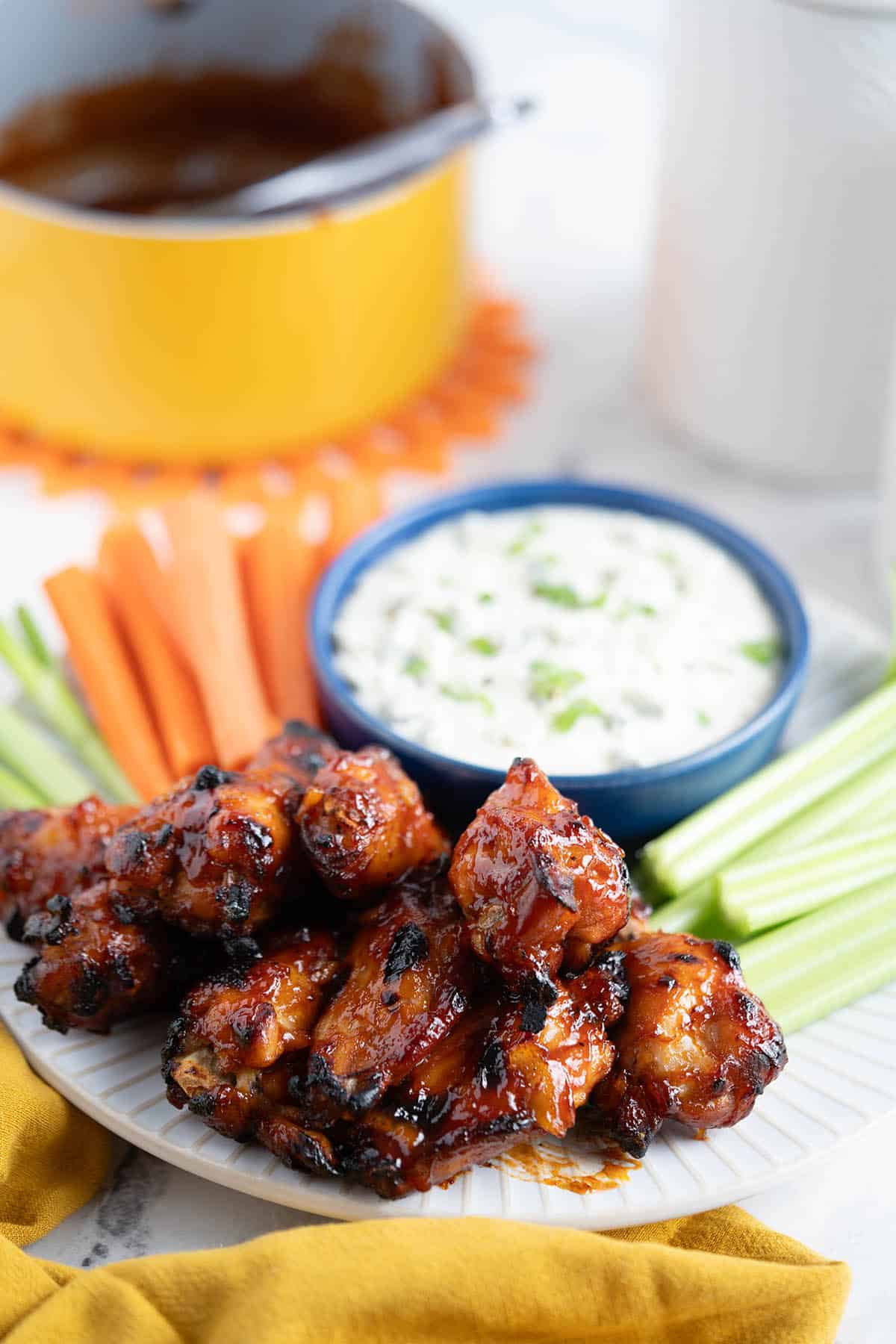 Sticky bbq chicken wings, sliced carrots and celery on a platter with blue cheese dip.