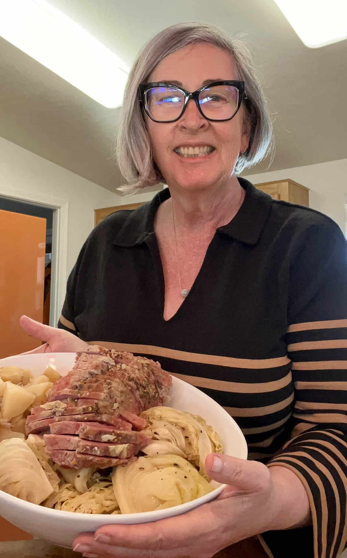 Blogger Deb Clark with a platter of Crock Pot Corned Beef and Cabbage ready to serve.