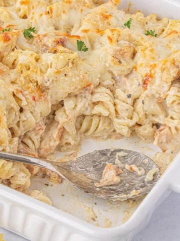 Dump and bake Garlic Parmesan Chicken Pasta in casserole dish, with a serving spoon.