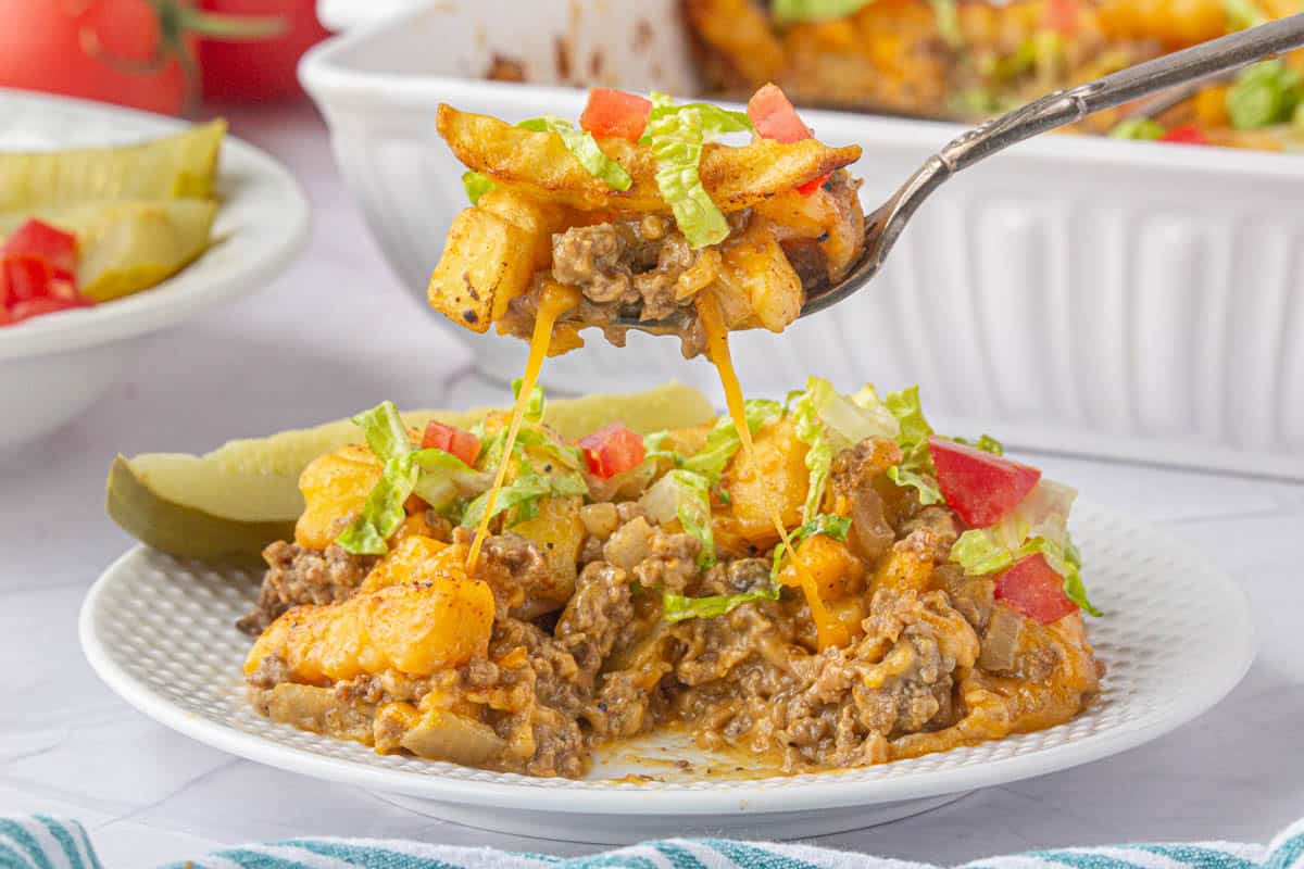 Hamburger French Fry Casserole on a plate with a fork filled with a bite to be taken.