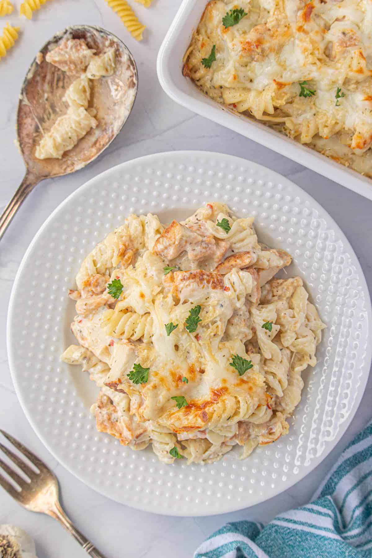 A plate filled with Garlic Parmesan Chicken Casserole with the full baking dish in the background.