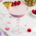 Pink Barbie Cocktail Drink topped with raspberries.