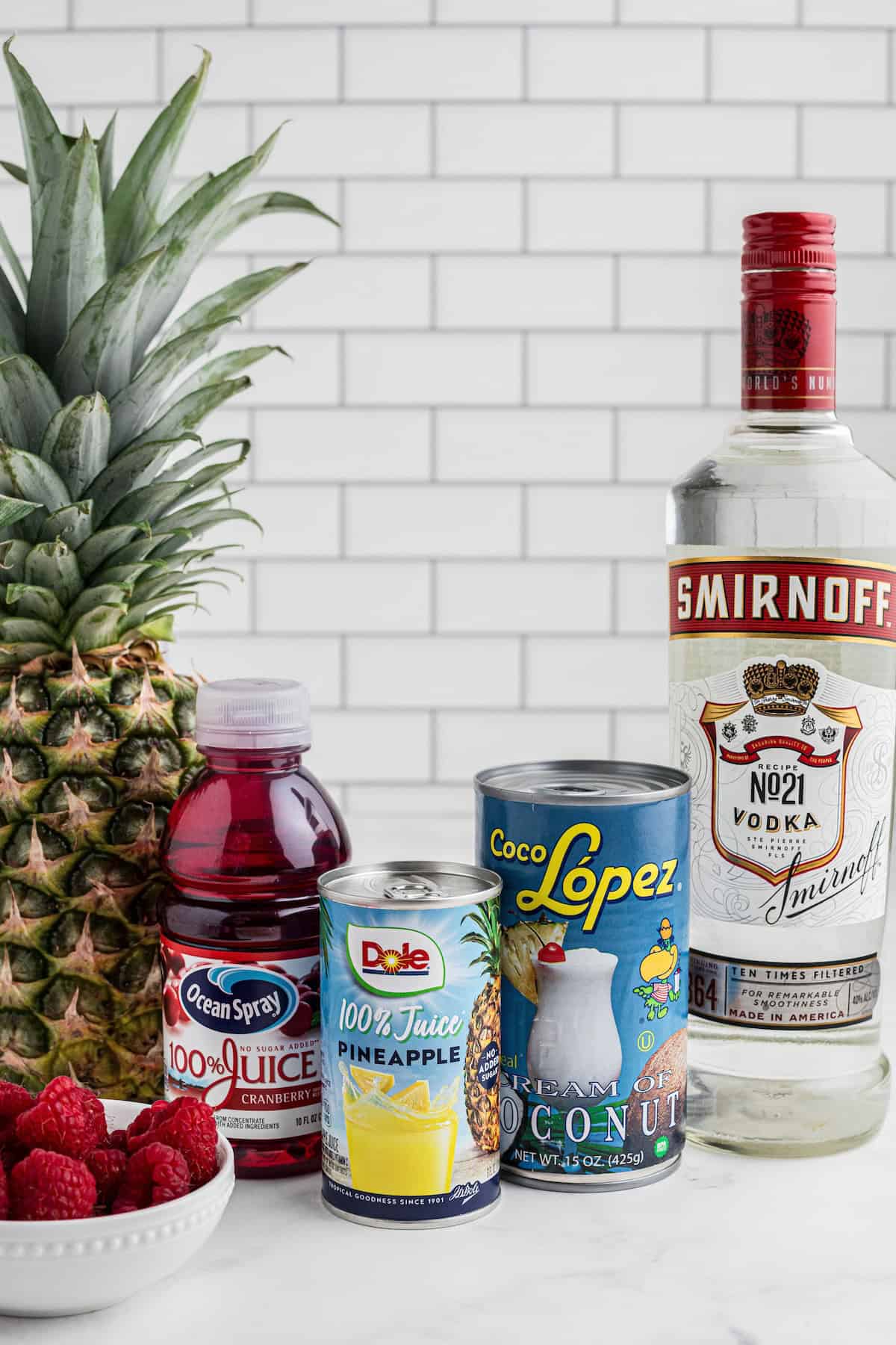 A list of ingredients that are needed for the recipe: Vodka, pineapple juice, coconut cream, cranberry juice and fresh raspberries.
