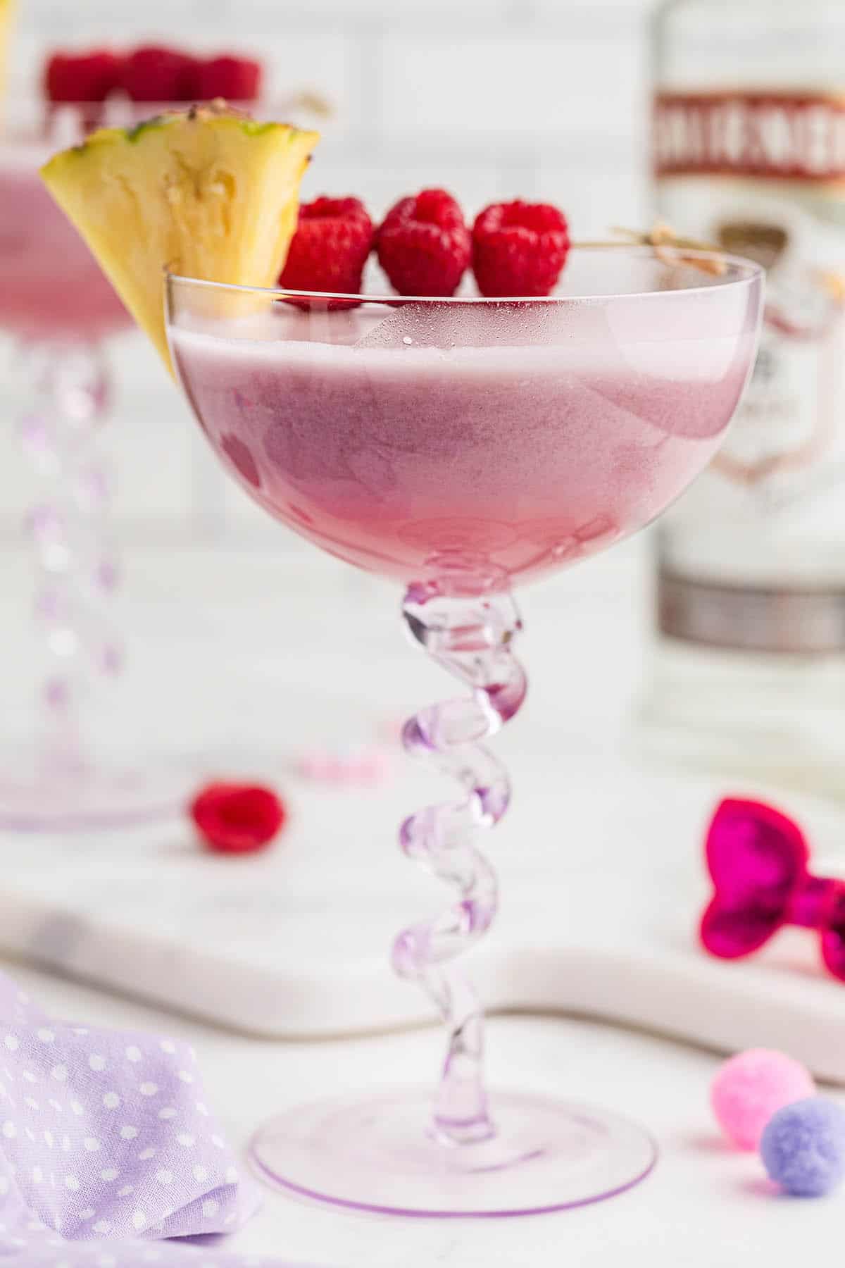 Pretty Pink Barbie Cocktail Drink garnished with raspberries and pineapple.