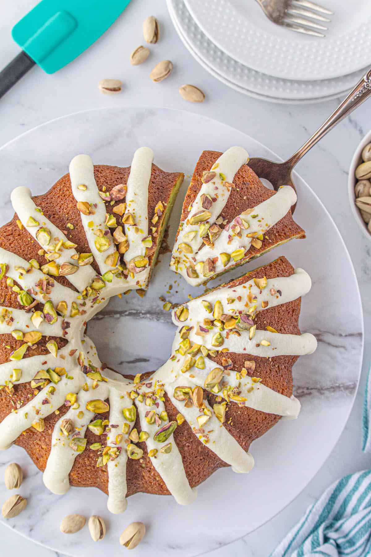 An overhead photo of pistachio bundt cake with a cake knife cutting a slice.