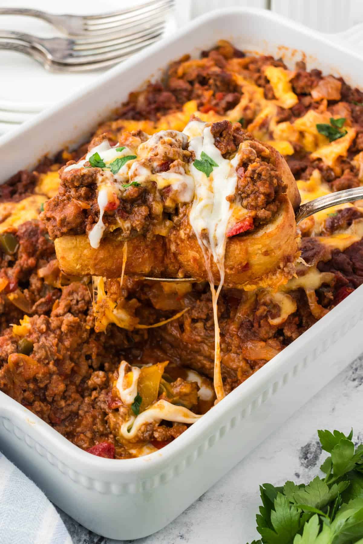 Sloppy Joe Garlic Bread Casserole in a baking dish, with a spatula scooping out a serving.