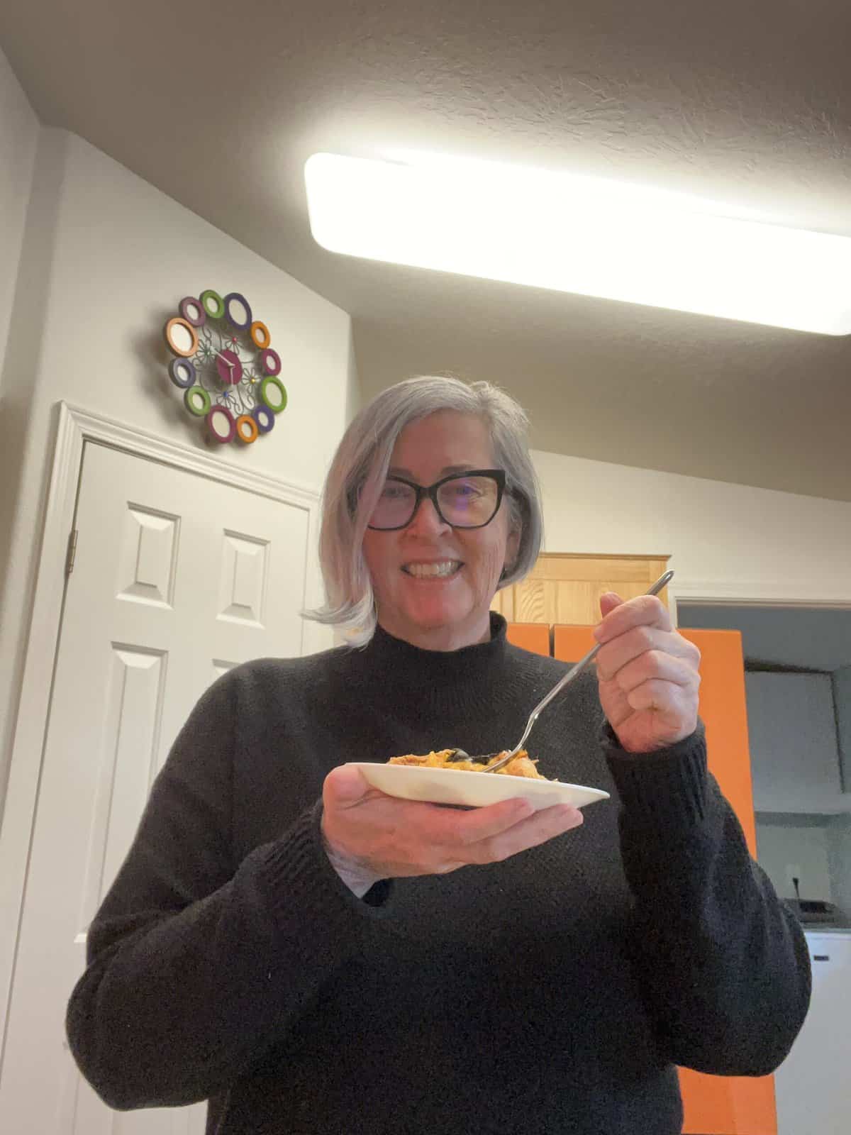 Blogger Deb Clark eating a plate Crockpot Chicken Enchilada Casserole.