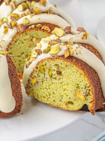 Nothing Bundt Pistachio Cake on a cake stand with a cake knife removing a slice.