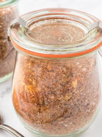 Jars of rub for ribs with a spoon for sprinkling the seasoning.