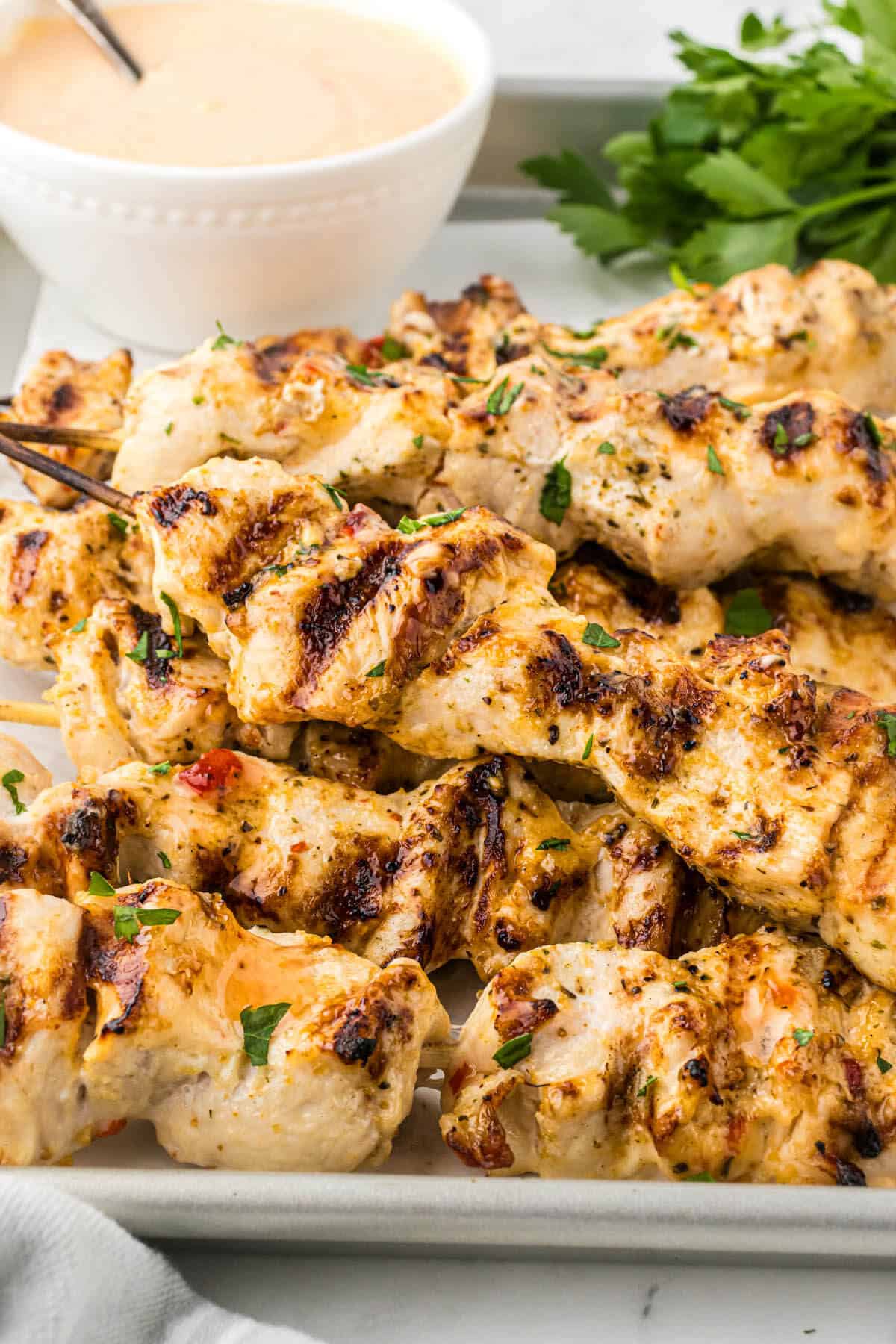 A platter filled with grilled chicken kabobs.