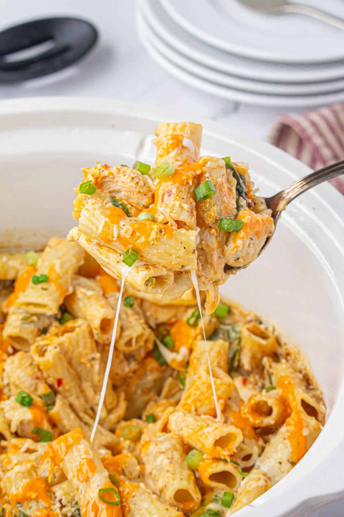Cheesy slow cooker buffalo chicken pasta with a serving spoon.