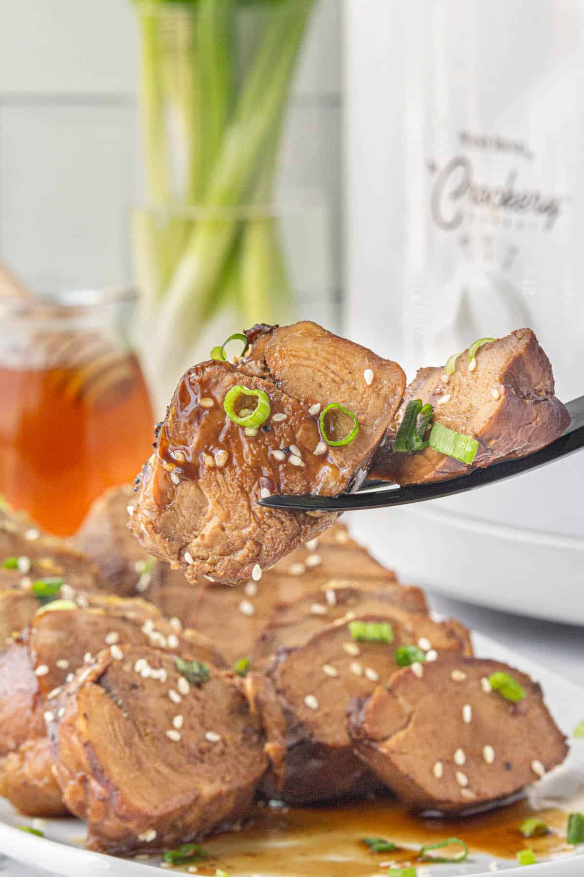 Sliced teriyaki pork loin on a platter, with a fork spearing two slices.