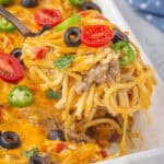 Cheesy taco spaghetti casserole with a spoon scooping out a serving.