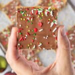 Hand holding a saltine cracker toffee piece of candy sliced into a square.