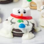 A melted snowman oreo cookie on a plate.