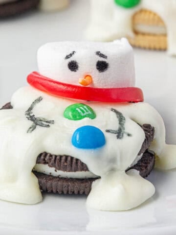 A melted snowman oreo cookie on a plate.