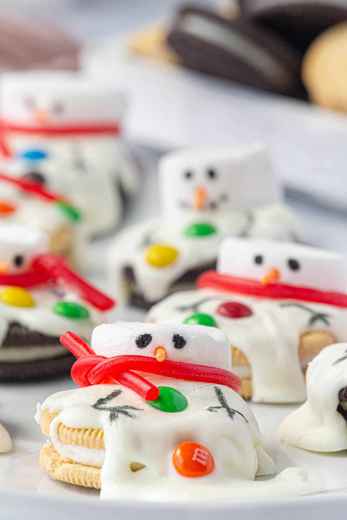 Super cute melted snowman cookies on a platter for a holiday cookie tray.